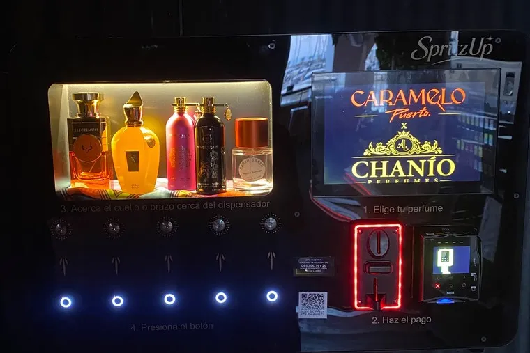 The machine again with its coin slot glowing red, showing the contactless terminal and the lit selection buttons.